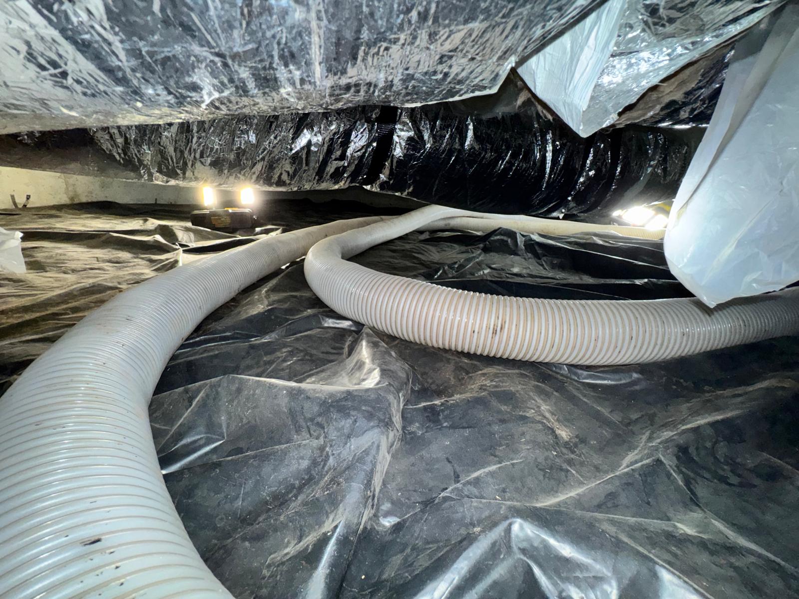 Residential crawlspace with vapor barrier ductwork and overhead insulation