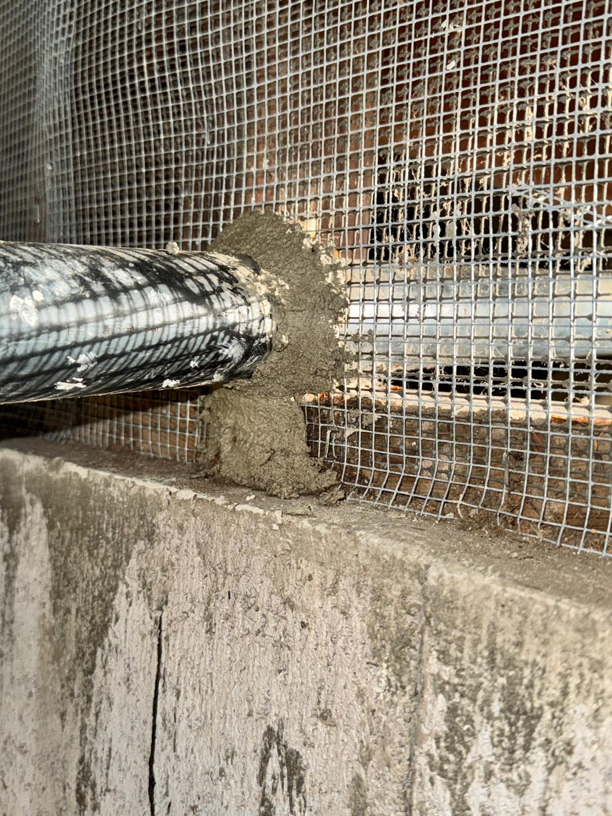Flexible duct penetration reinforced with metal mesh and mortar